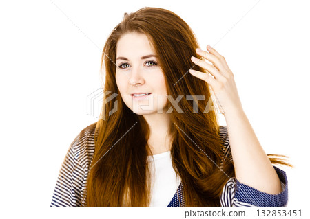 Young woman touching her long brown hair Young woman touching her long brown hair 132853451