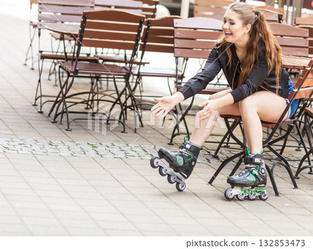 Young woman sitting wearing roller skates 132853473