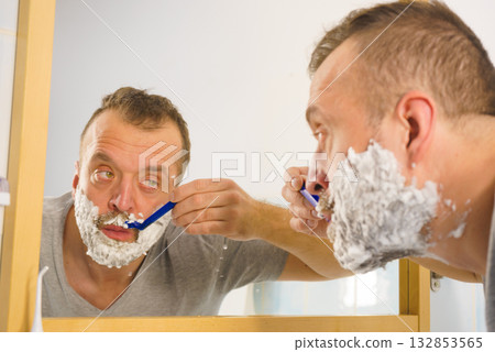 Guy shaving his beard in bathroom 132853565