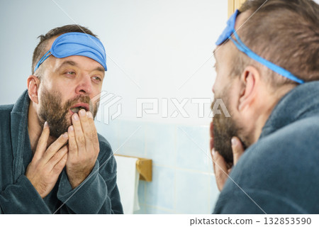 Sleepy man looking at mirror and yawning Sleepy man looking at mirror and yawning 132853590