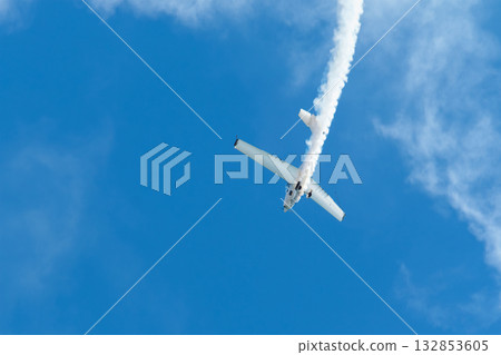 Stunt aerobatic plane performing stunts in blue sky with smoke trail. Concept of speed, difficulty, precision, risk, challenge Stunt aerobatic plane performing stunts in blue sky with smoke trail. Concept of speed, difficulty, precision, risk, challenge 132853605