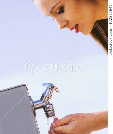 Woman drinking water from street tap 132853643