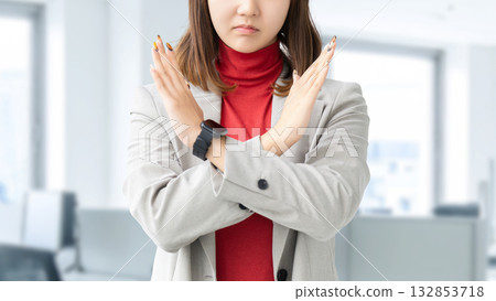 A woman/businesswoman with a troubled expression making a cross pose with her hand 132853718