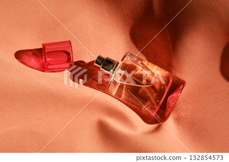 A pink perfume bottle on a soft reddish background. 132854573