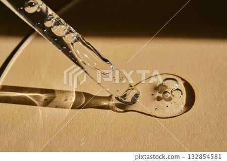 A pipette with cosmetic serum on a beige background. A pipette with cosmetic serum on a beige background. 132854581