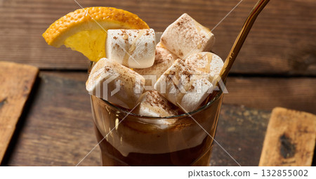 A glass of hot chocolate with white marshmallow pieces on a wooden table A glass of hot chocolate with white marshmallow pieces on a wooden table 132855002