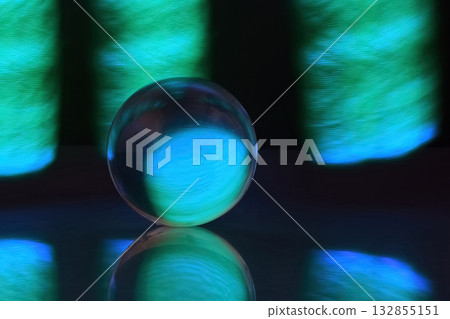 Glowing Orb Reflections. A glowing glass orb set against a backdrop of vibrant blue and green light. Glowing Orb Reflections. A glowing glass orb set against a backdrop of vibrant blue and green light. 132855151