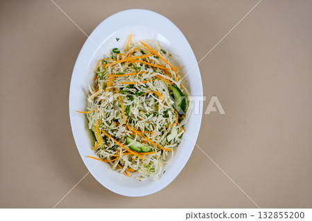 Cabbage carrot salad Fresh salad of white cabbage with carrots dressed with olive oil close-up in a bowl on the table. Vertical top view from above Cabbage carrot salad Fresh salad of white cabbage with carrots dressed with olive oil close-up in a bowl on the table. Vertical top view from above 132855200