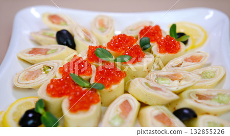 thin pancakes with caviar and red fish Delicious thin pancakes with red caviar on plate, closeup 132855226