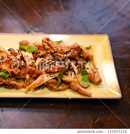 Asian appetizer pig pork ears with sesame seeds, green onion and spicy sauce. Isolated on white background 132855228