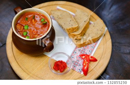 Traditional Indian Punjabi dish Dal makhani with lentils and beans in black bowl served with naan flat bread, fresh cilantro and two spoons on blue concrete rustic table top view. Space for text Traditional Indian Punjabi dish Dal makhani with lentils and beans in black bowl served with naan flat bread, fresh cilantro and two spoons on blue concrete rustic table top view. Space for text 132855230