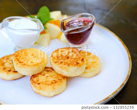 Homemade pancakes with yoghurt, berries and raspberry jam. Pancake day breakfast on beige tile background, top view. Vertical 132855239