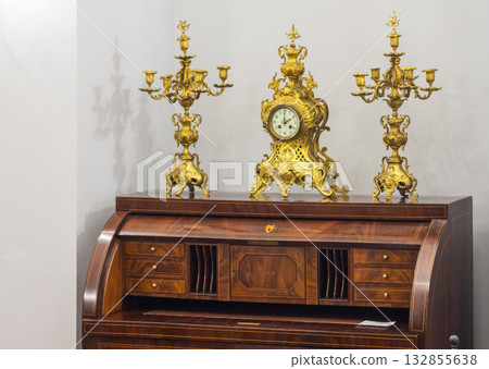 an antique French gilt bronze Rococo clock set, likely from the 19th century, with a central mantel clock and a pair of flanking candelabra. an antique French gilt bronze Rococo clock set, likely from the 19th century, with a central mantel clock and a pair of flanking candelabra. 132855638