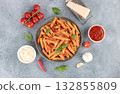 Italian pasta penne arrabiata with tomato sauce and chili pepper on blue background. Top view. Copy space 132855809