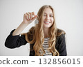 Smiling young woman holds keychain while showing excitement for new beginnings in a bright, minimalistic setting 132856015