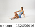 Young woman in workout attire poses confidently in a studio setting during a fitness session 132856016