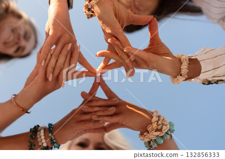 Hands team collaboration forming star shape against blue sky symbolizing unity friendship and support with copy space Hands team collaboration forming star shape against blue sky symbolizing unity friendship and support with copy space 132856333