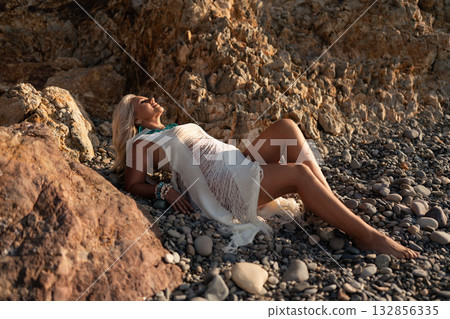 Woman beach summer, relaxing on pebble shore with rocky cliffs, enjoying a peaceful vacation in natural beauty Woman beach summer, relaxing on pebble shore with rocky cliffs, enjoying a peaceful vacation in natural beauty 132856335