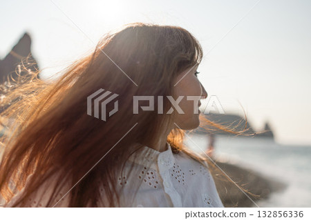Woman beach ocean, barefoot in blue dress walking on pebble beach, gentle waves lapping, summer relaxation 132856336