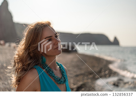 Woman, beach, golden hour, beautiful woman standing on pebble beach by the sea at sunset, looking thoughtfully at the horizon Woman, beach, golden hour, beautiful woman standing on pebble beach by the sea at sunset, looking thoughtfully at the horizon 132856337