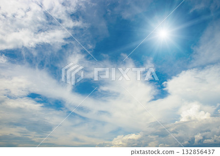 Weather background with radiant sun, blue sky, and scattered clouds symbolizing warmth, clarity, and pleasant conditions 132856437