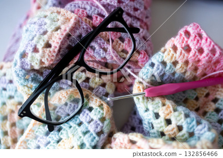 Colorful crochet project with glasses and hook in pastel yarn 132856466