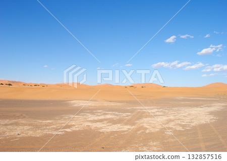 A desert landscape with a blue sky and footprints in the sand A desert landscape with a blue sky and footprints in the sand 132857516