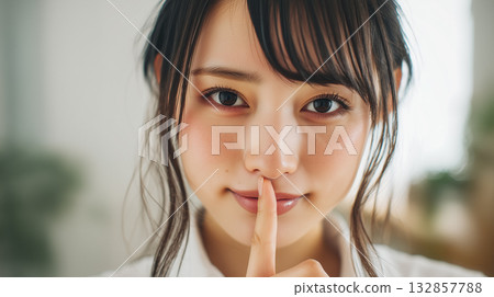 Smiling woman making a secret gesture | Visuals conveying secrets, silence, and secrecy 132857788