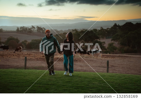 A Couple Enjoying a Romantic Walk Hand in Hand at Sunset in a Scenic Landscape 132858169