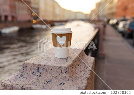 White cup of natural coffee with carved heart on bridge near embankment of Fontanka river in St. Petersburg on sunset White cup of natural coffee with carved heart on bridge near embankment of Fontanka river in St. Petersburg on sunset 132858363