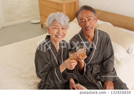 Senior couple having a drink in the bedroom (alcohol, drinking) Senior couple having a drink in the bedroom (alcohol, drinking) 132858830