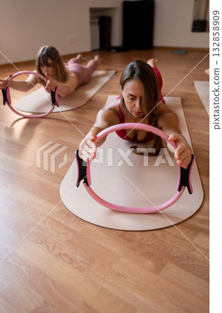 Exercises with pilates ring. Woman doing aerobics workout at pilates studio with panoramic windows. Exercises with pilates ring. Woman doing aerobics workout at pilates studio with panoramic windows. 132858909