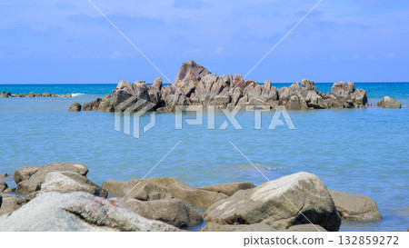 Close-up of a Rugged Rocky Island Outcrop Emerging from the Blue-Green Tropical Ocean Close-up of a Rugged Rocky Island Outcrop Emerging from the Blue-Green Tropical Ocean 132859272