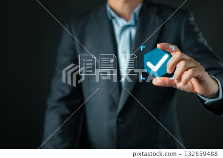 A businessman in a suit selects a glowing blue checkmark icon among digital document icons, representing successful validation, approval, completion, and verified document processing. A businessman in a suit selects a glowing blue checkmark icon among digital document icons, representing successful validation, approval, completion, and verified document processing. 132859488