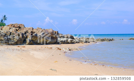 Sandy Tropical Beach with Large Rocky Boulders on the Shoreline and Clear Blue Horizon 132859508