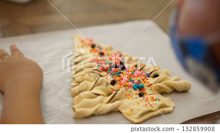Child decorating Christmas tree shaped pastry with colorful sprinkles, festive baking activity at home, homemade dessert preparation on parchment paper, family holiday cooking fun with creative sweet Child decorating Christmas tree shaped pastry with colorful sprinkles, festive baking activity at home, homemade dessert preparation on parchment paper, family holiday cooking fun with creative sweet 132859908