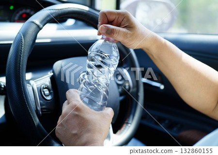 Asian woman driver holding water bottle in car. Asian woman driver holding water bottle in car. 132860155