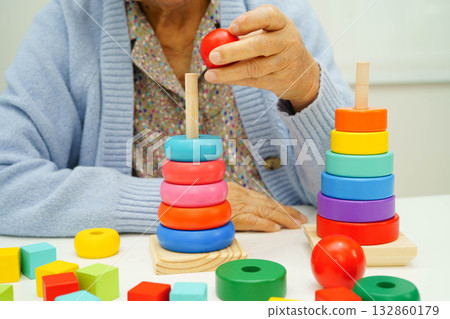 Asian elderly woman playing enhancing skill board game. Asian elderly woman playing enhancing skill board game. 132860179