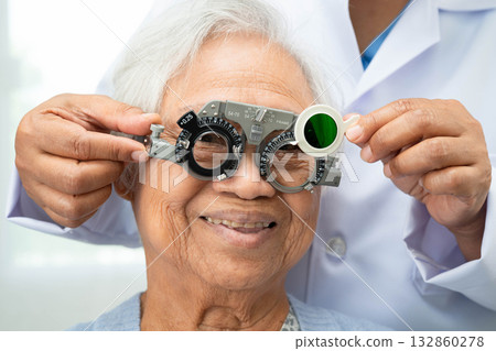 Asian senior woman wearing ophthalmic vision eye test and using optical trial frame. 132860278