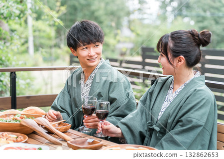 Young Asian couple at a Japanese inn or hot spring inn having a meal on the balcony or wooden deck (travel and travel) 132862653