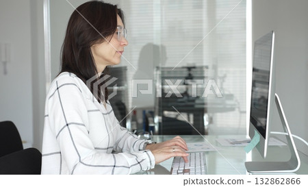 Woman working on desktop computer at office desk, typing and analyzing data, focusing on business tasks and professional work. Businesspeople concept Woman working on desktop computer at office desk, typing and analyzing data, focusing on business tasks and professional work. Businesspeople concept 132862866