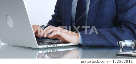Professional businessman working on laptop computer, typing on keyboard in modern office, managing business tasks. Business people concept Professional businessman working on laptop computer, typing on keyboard in modern office, managing business tasks. Business people concept 132862911