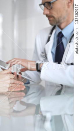 Male doctor consulting female patient, discussing diagnosis and medical history with digital tablet in clinic. Medicine and health care 132862957