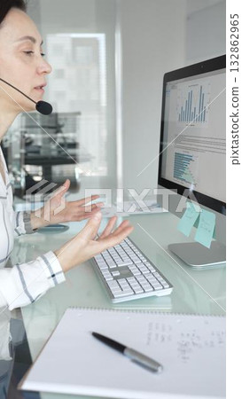 Female call center agent wearing a headset, assisting customers remotely and participating in a virtual office meeting. Professional customer support and business services 132862965