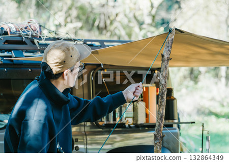 Male camper setting up a tent at a campsite in autumn and winter Male camper setting up a tent at a campsite in autumn and winter 132864349