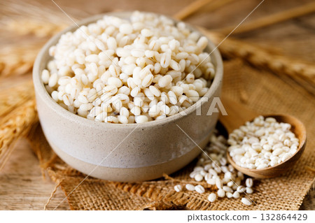 Closeup of cooked barley grains on wooden table. Closeup of cooked barley grains on wooden table. 132864429