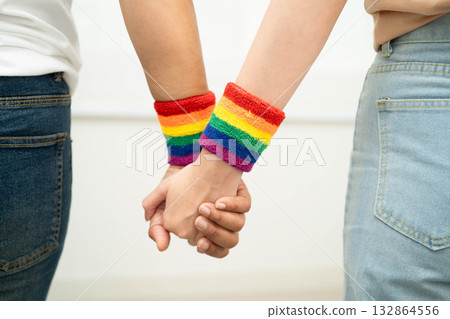 Asian LGBT couple woman holding hand wearing rainbow wristband. Asian LGBT couple woman holding hand wearing rainbow wristband. 132864556