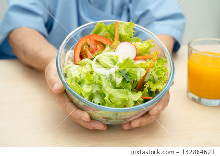 Asian elderly woman patient eating salmon stake and vegetable salad for healthy food in hospital. 132864621