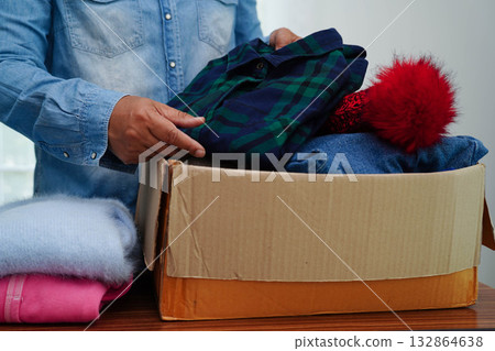 Clothes donations in cardboard box for volunteer. Clothes donations in cardboard box for volunteer. 132864638