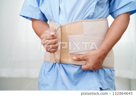 Asian senior wearing elastic support belt can help reduce back pain. Asian senior wearing elastic support belt can help reduce back pain. 132864645